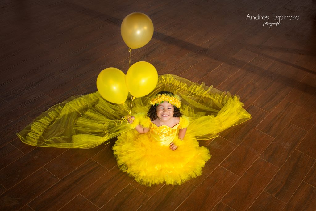 Niña de traje amarillo con globos en toma contrapicada