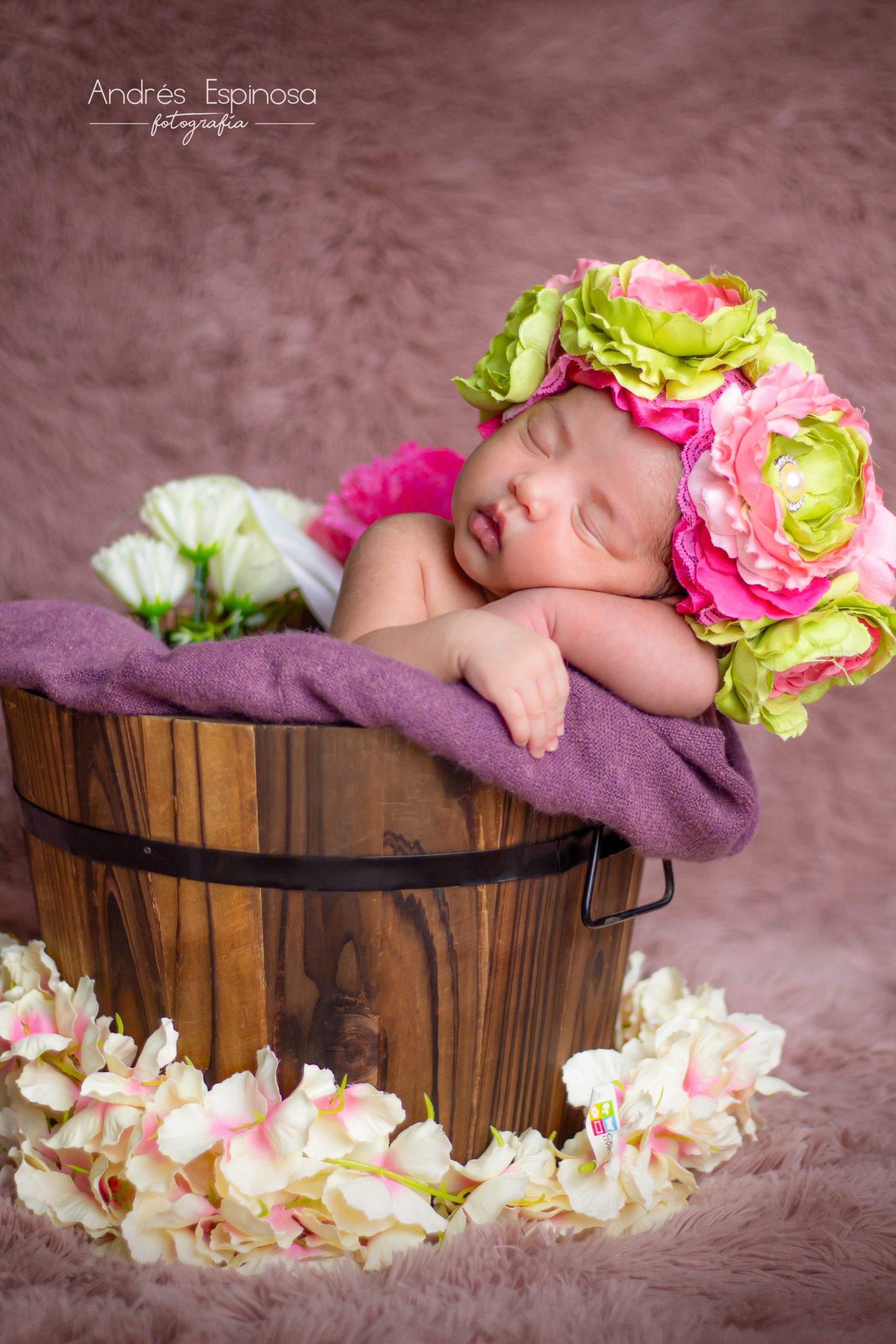 Bebé recién nacida con tocado de flores dentro de un cubo
