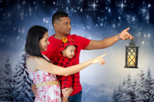 Papá y mamá cargan bebe mientras siguen linterna en noche nevada